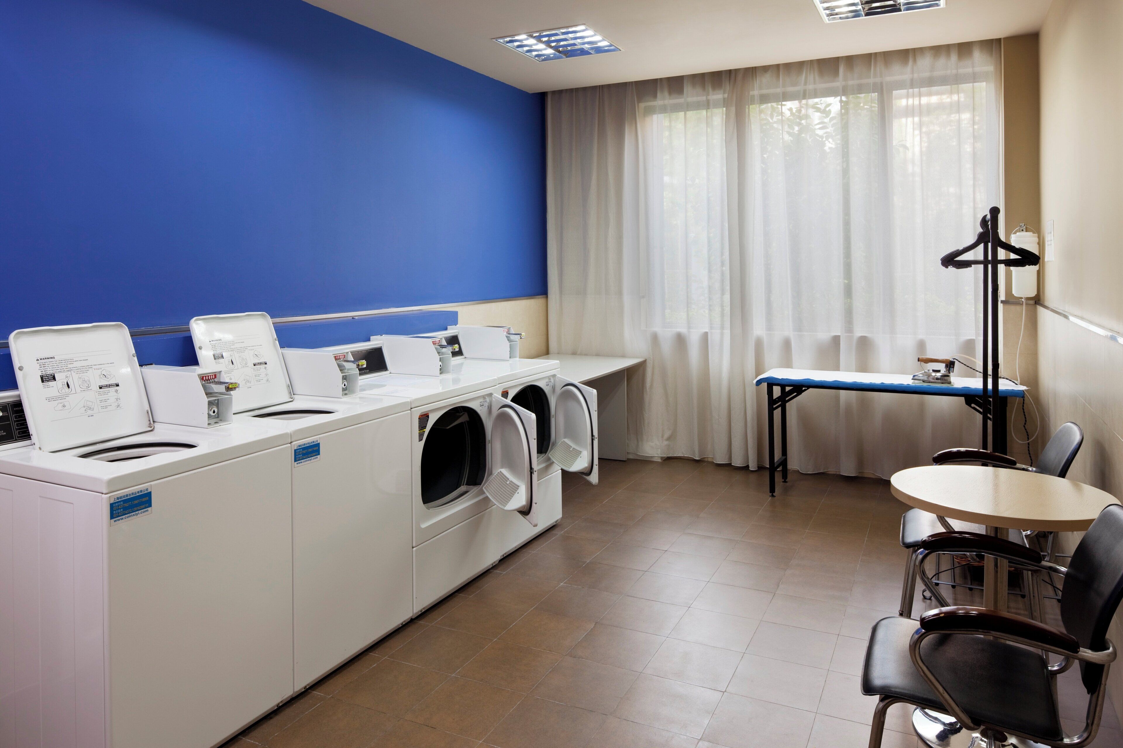 A laundry room with a blue wall, a table, chairs, and a drying rack.