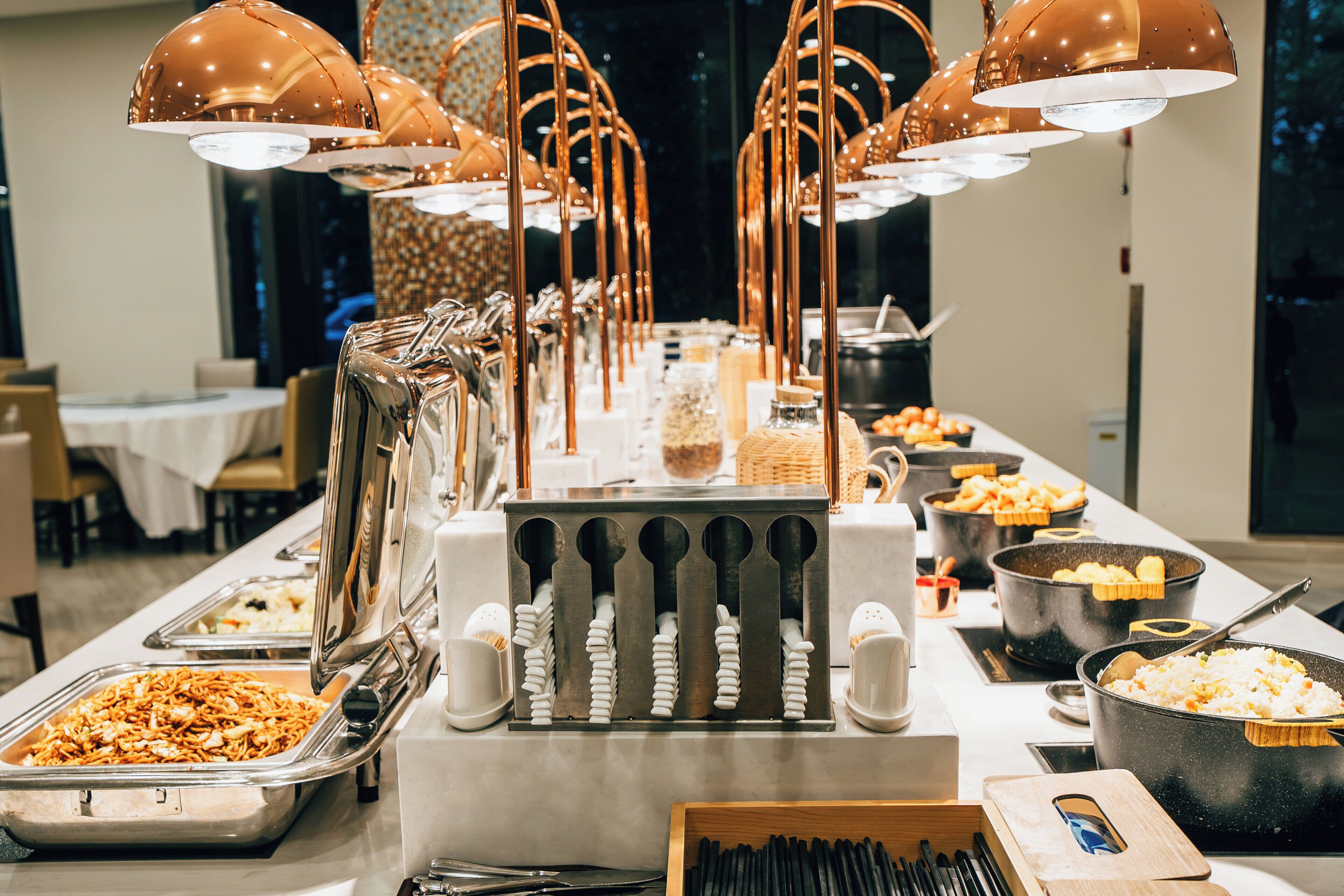 A buffet setup with various food stations and utensils.