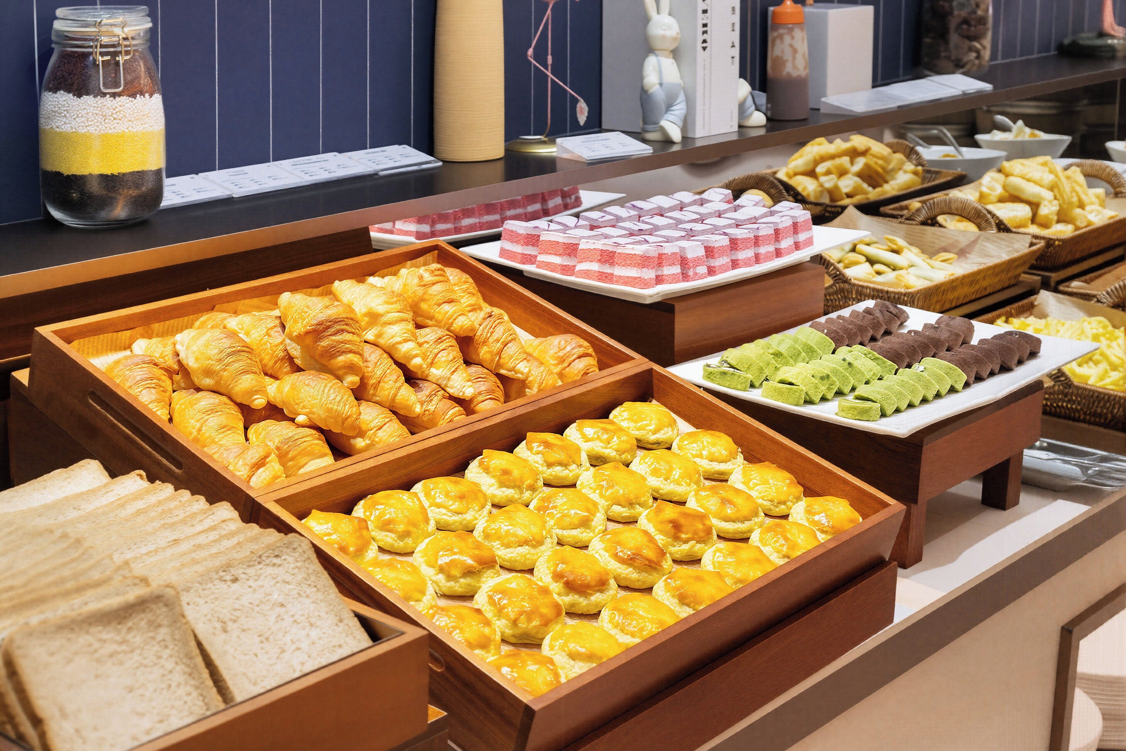 Un bufé con diversas opciones de panadería, incluyendo cruasanes, muffins y pasteles.