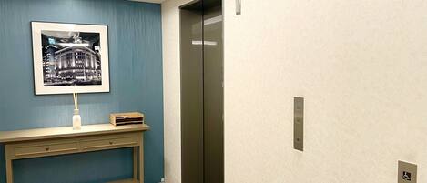 A modern elevator with a control panel and a wall-mounted sign indicating the floor number.