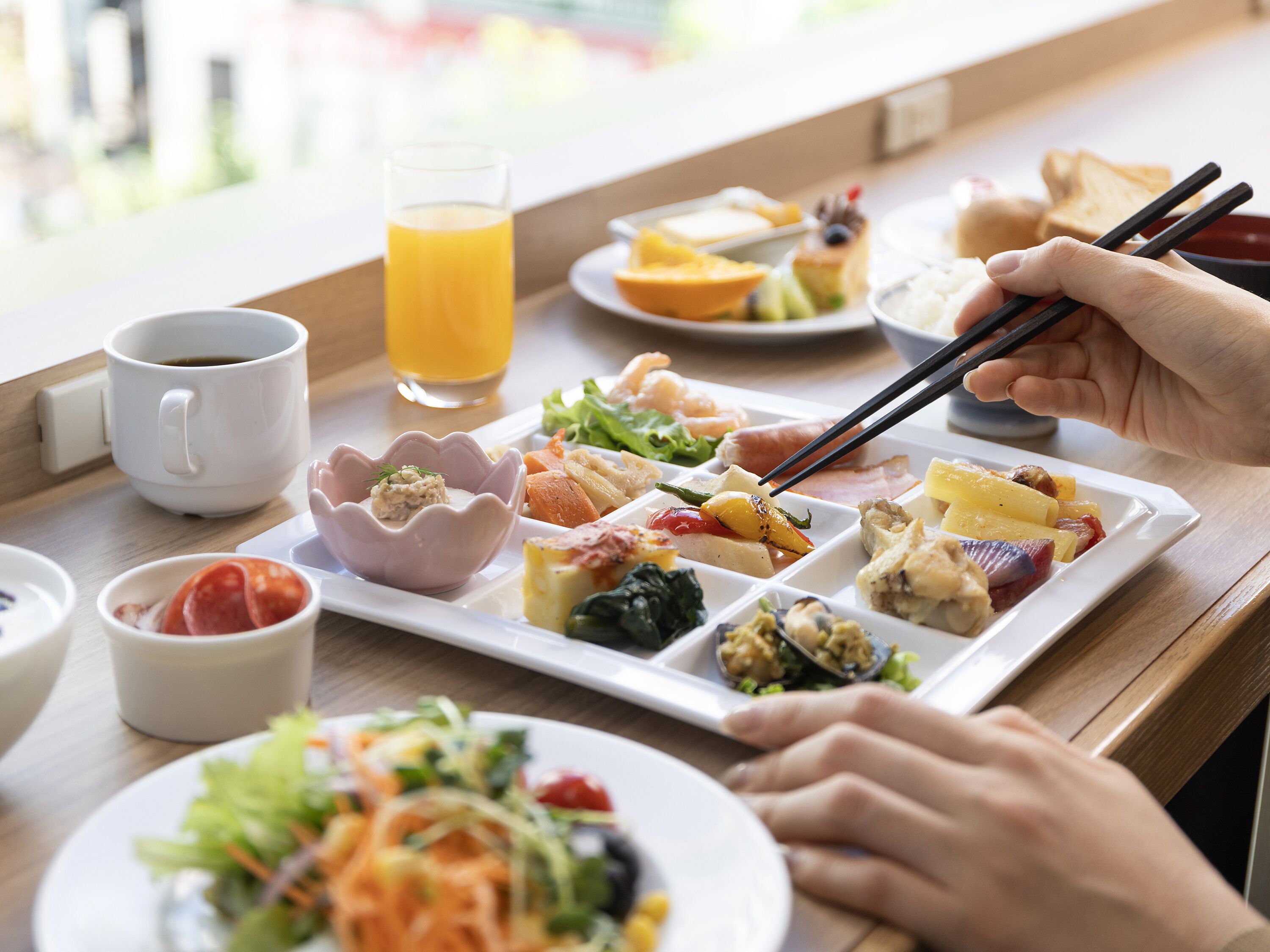 A meal with various dishes and a glass of orange juice on a table.