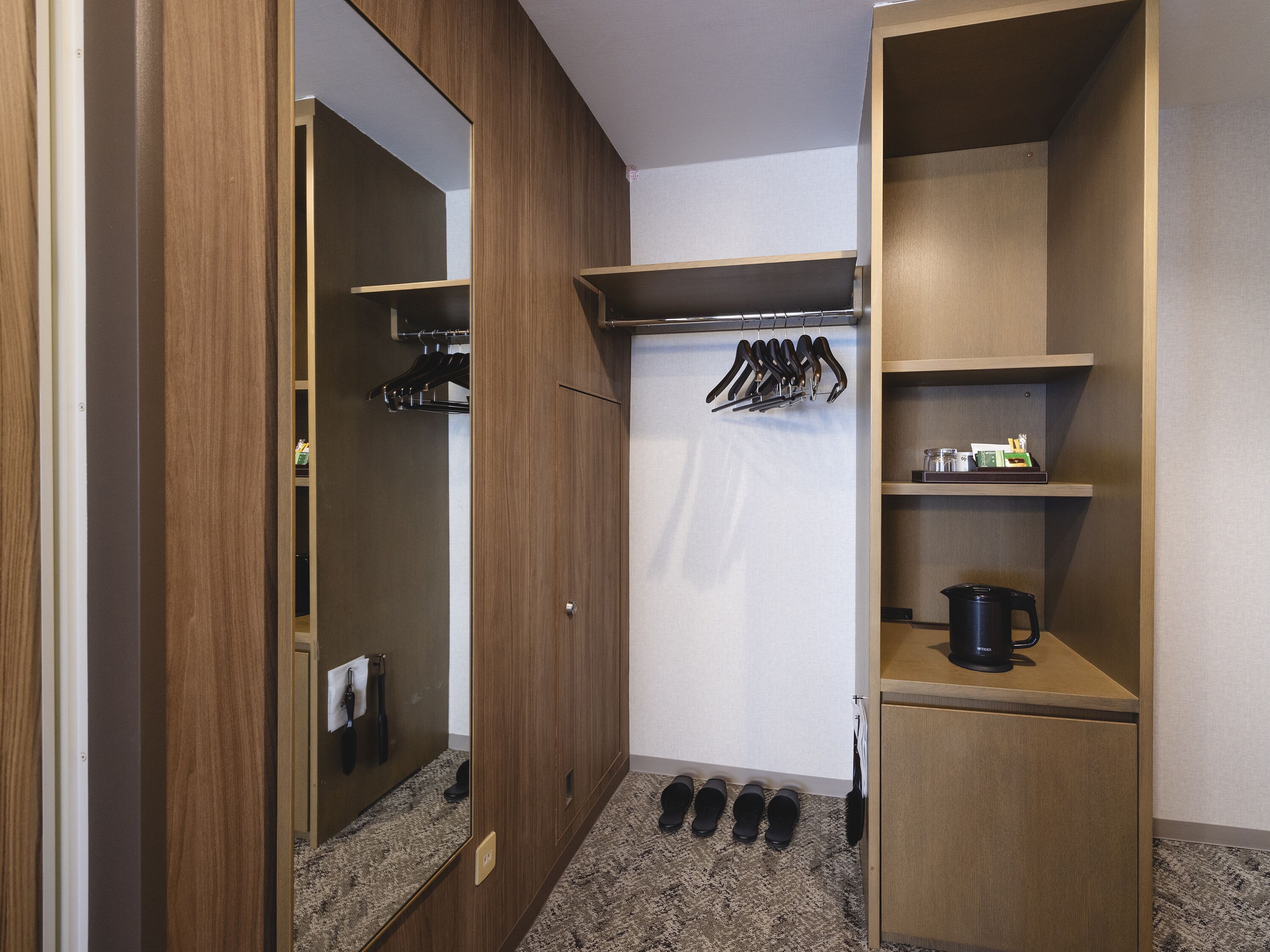 Un dressing avec des portes en bois, un porte-chaussures et des étagères contenant divers objets.