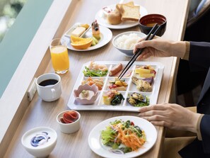 A meal tray with various dishes including rice, vegetables, and meat, and a person using chopsticks. - Hotel Gracery Ginza (Tokyo)