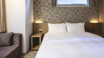 A hotel room with a bed, a nightstand, a chair, and a window with curtains.