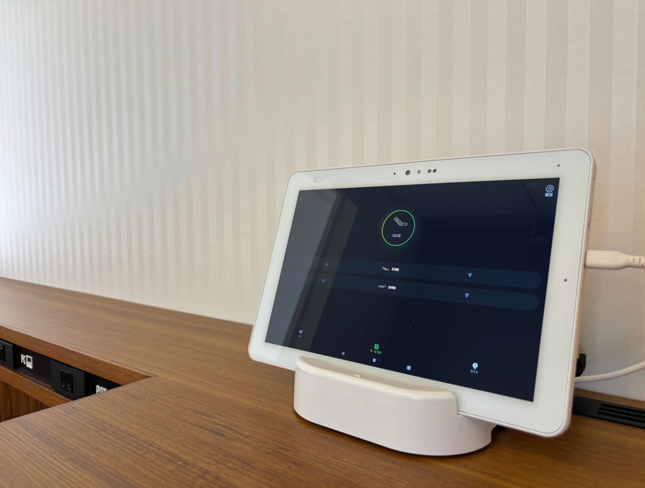 A tablet on a stand with a wooden surface, displaying a user interface with icons and text.
