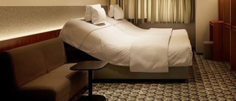 Habitación de hotel con cama, sofá, mesita y suelo estampado.