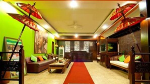 A hotel lobby with a red carpet, sofas, and a reception desk.