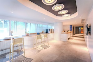 Un espace d’accueil moderne doté d’un bar, de sièges et d’une grande fenêtre.
