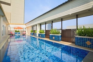 Ein Swimmingpool mit blauen Fliesen, umgeben von Liegestühlen und Kübelpflanzen.
