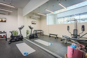 Een moderne sportschool met fitnessapparatuur, een spiegel en een uitzicht op de stad door grote ramen.