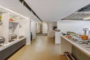 Eine moderne Küche mit einer langen Arbeitsplatte, ausgestattet mit einer Kaffeemaschine und verschiedenen Lebensmitteln.