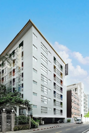 Un immeuble à plusieurs étages doté d’une architecture moderne, caractérisé par une série de balcons et de fenêtres.