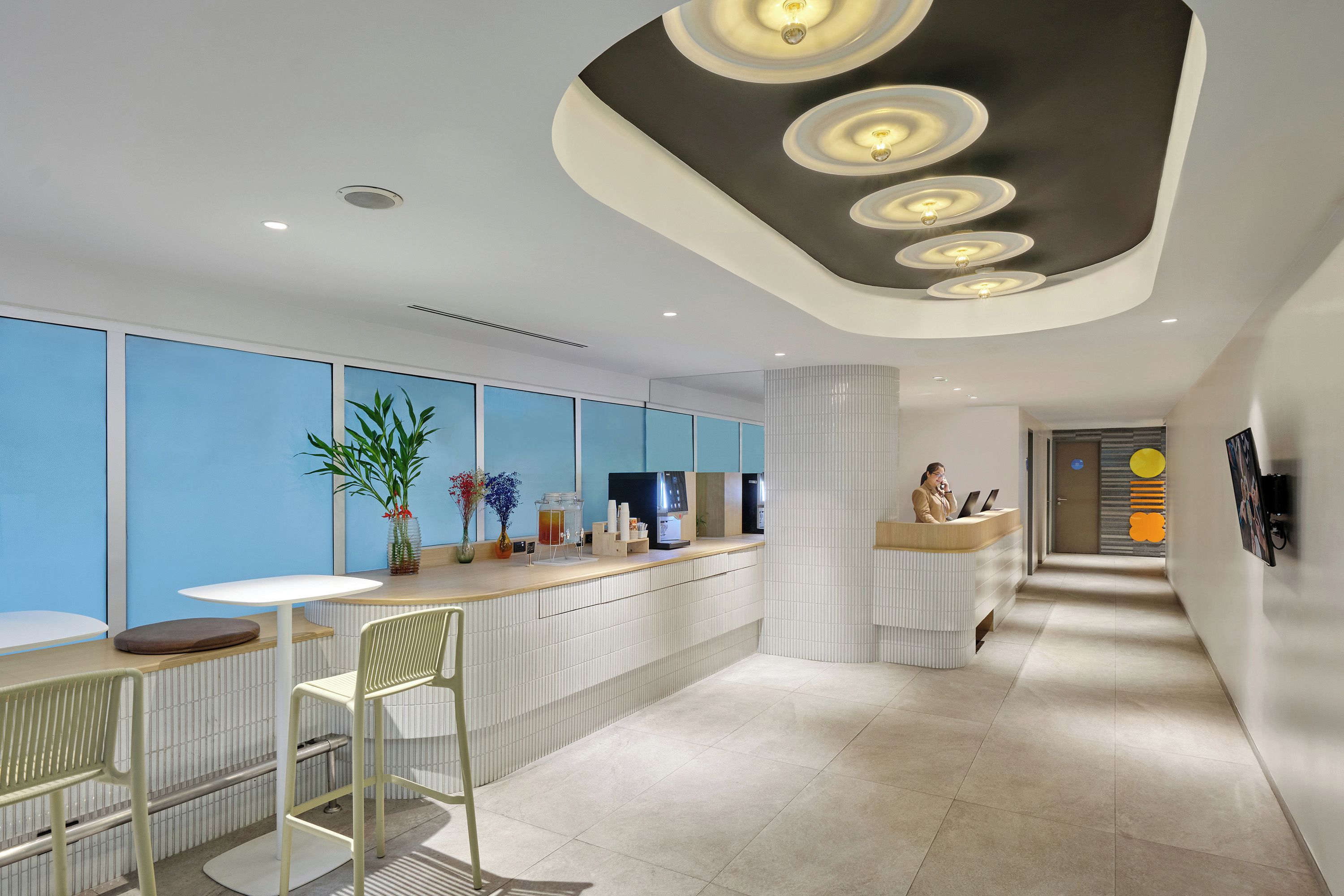 A modern reception area with a counter, seating, and a decorative ceiling.