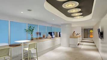 A modern reception area with a counter, seating, and a decorative ceiling.
