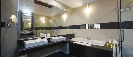 A modern bathroom with two sinks, a large bathtub, and a glass shower enclosure.