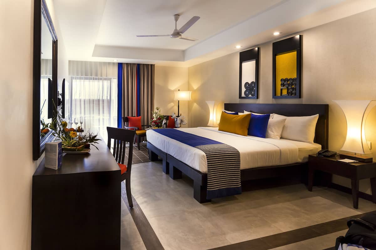 A modern hotel room with a bed, bedside tables, a desk, and a chair.