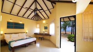 Habitación de hotel con una cama grande, escritorio, espejo y vista a la playa.