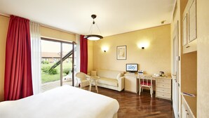 Een hotelkamer met een bed, een bureau, een stoel, een bank en uitzicht op het buiten.
