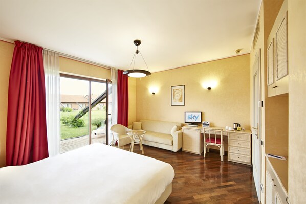Habitación de hotel con cama, escritorio, sillón, sofá y vistas al exterior.