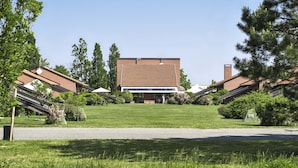 Een gebouw met een plat dak en bakstenen muren, omringd door een verzorgd gazon en bomen.