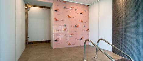 A modern interior with a tiled floor, a pink wall with a pattern, and a metal railing.