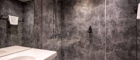 Une salle de bain moderne avec un grand lavabo blanc, une douche en verre et un mur à texture.