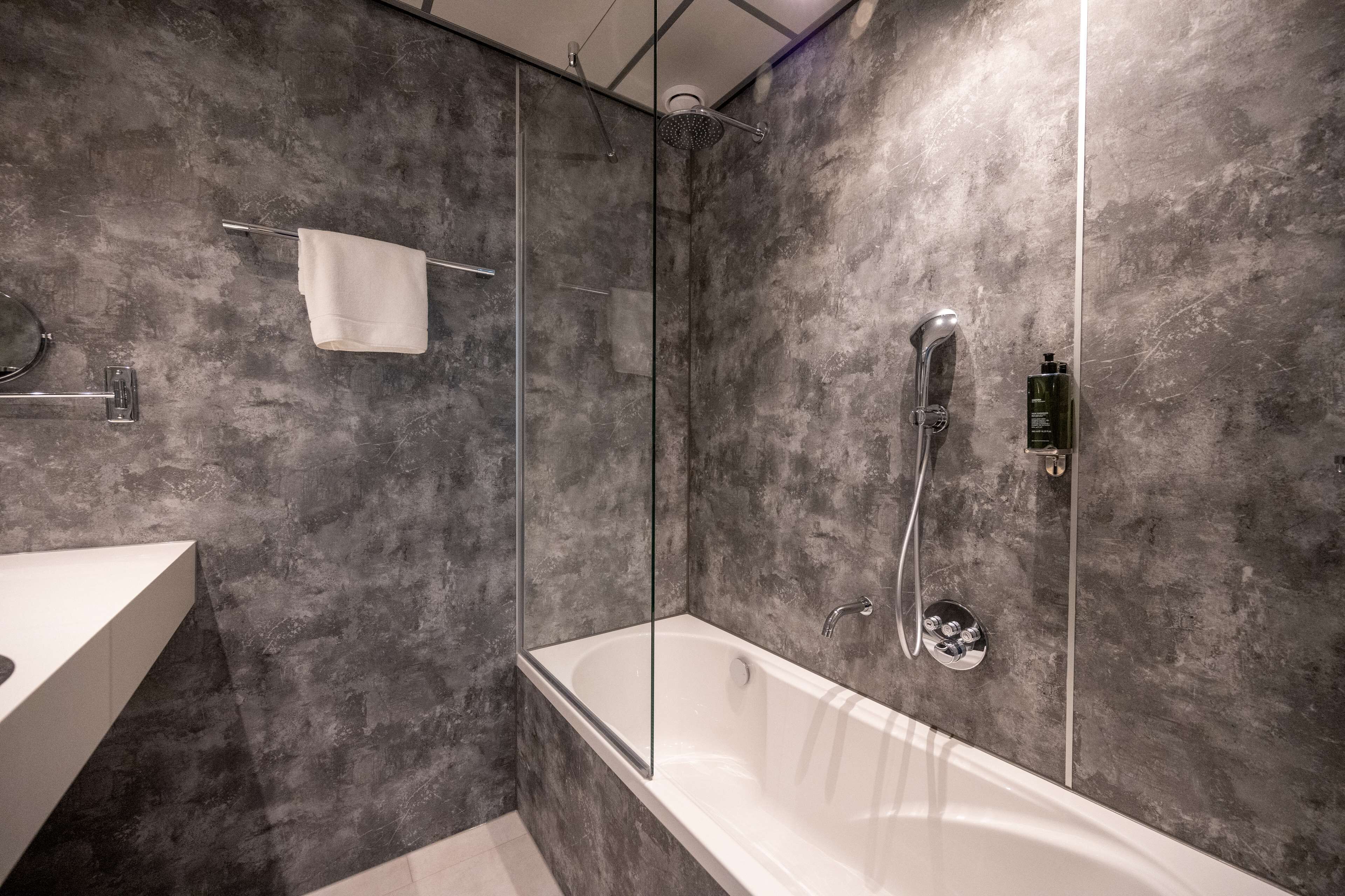 A modern bathroom with a glass-enclosed shower, a freestanding bathtub, and a white vanity.