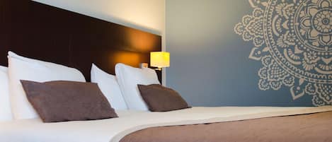 Habitación de hotel con una cama bien hecha, cabecero, pared con diseño decorativo y lámpara de noche.