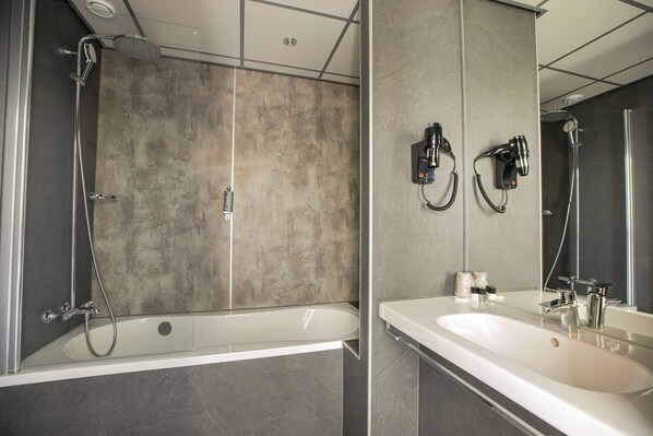 A modern bathroom with a bathtub, a shower, and a large mirror.