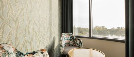 A room with a large window, a round table, and two patterned sofas.