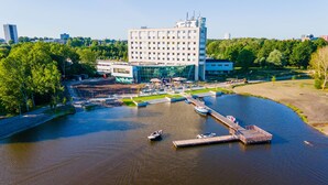 Hotel a la orilla del río con muelle, un bote y zona de parque.