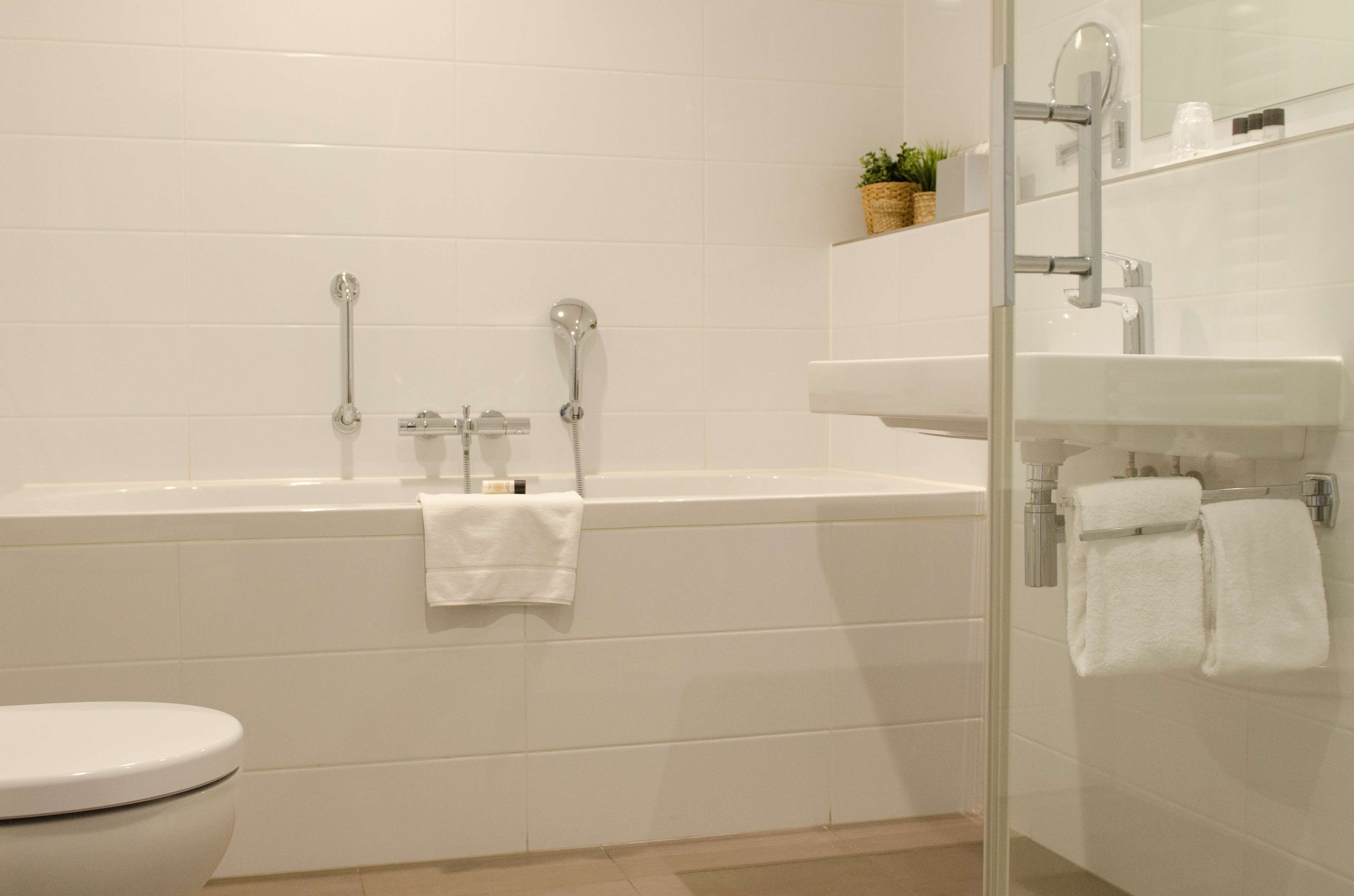 A modern bathroom with a white bathtub, a glass-enclosed shower, and a white sink.