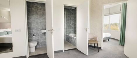 A modern hotel room with a bathroom, a shower, a toilet, and a bed.