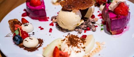 Un plato de postres con diversas golosinas, incluyendo helado y fruta.
