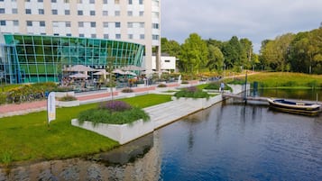 Hotel aan de rivier met een glazen gevel, terras en een steiger.