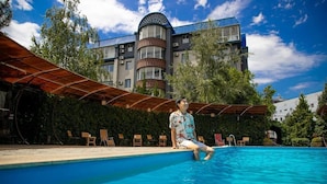 Eine Person sitzt am Pool, im Hintergrund ein Gebäude.