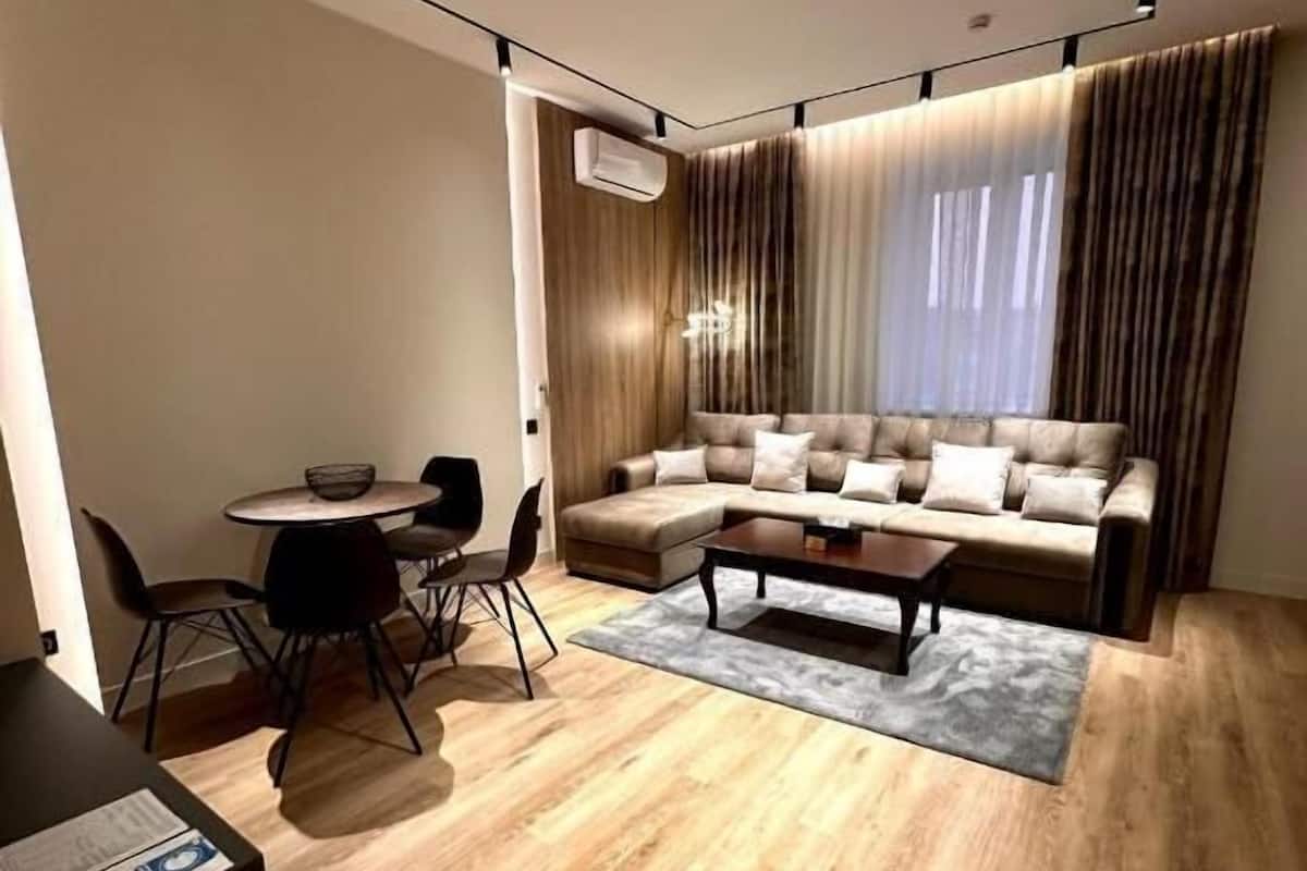 A modern living room with a sectional sofa, a coffee table, and a dining area with chairs and a table.