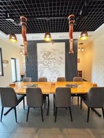 Un salón de conferencias con una larga mesa de madera, seis sillas y un gran mural en la pared.