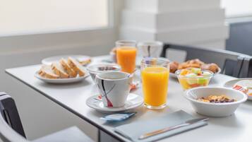 A breakfast table with various food items and a glass of orange juice.