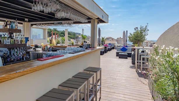An outdoor bar area with a wooden deck, bar counter, and seating. - Hôtel Impérial (Sète)