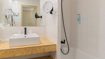 A modern bathroom with a white sink, mirror, and shower.