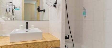 Un baño moderno con lavamanos, espejo y ducha blancos.