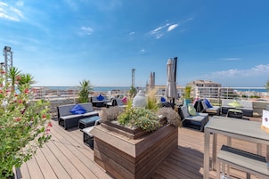 Una terraza en la azotea con mobiliario exterior, una maceta decorativa y vistas al mar.