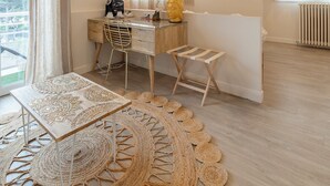 A modern living room with a wooden desk, a sofa, and a large woven rug. - Hôtel Impérial (Sète)