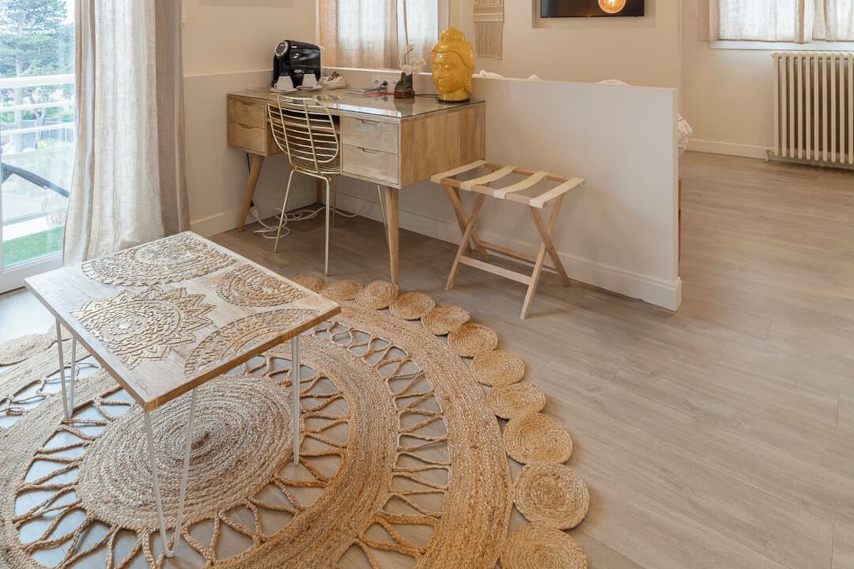 A modern living room with a wooden desk, a sofa, and a large woven rug.