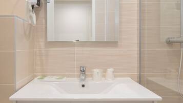 A bathroom with a white sink, a mirror, and a handheld hair dryer mounted on the wall.