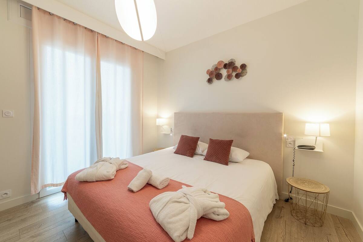 A hotel room with a large bed, two bedside lamps, a wall-mounted light fixture, and a small round table.