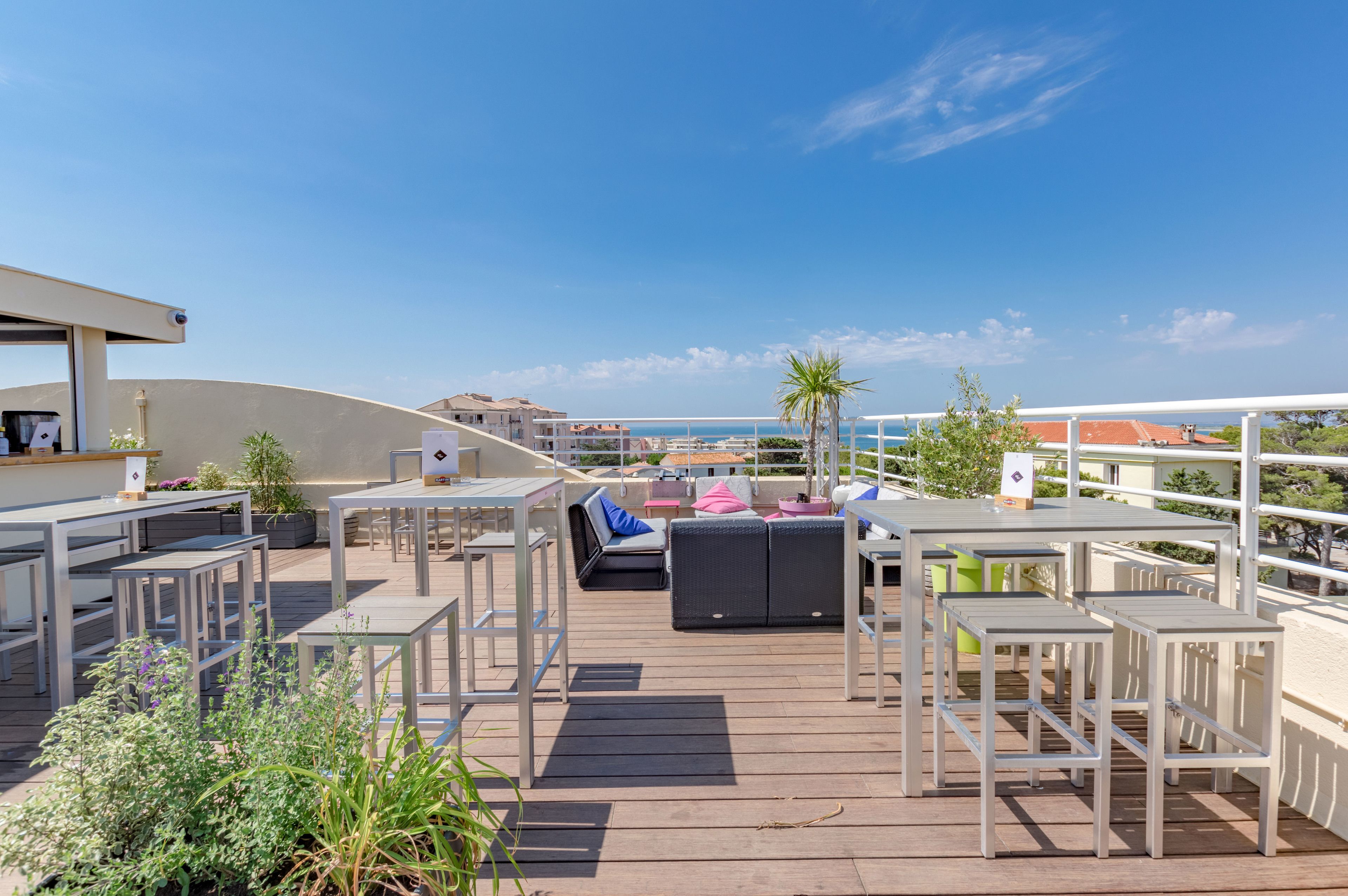 A rooftop terrace with outdoor seating, a pool, and a view of the sea.