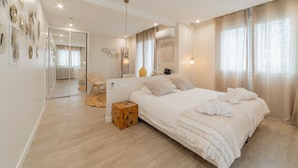 A modern bedroom with a large bed, a wooden side table, and a chair. - Hôtel Impérial (Sète)