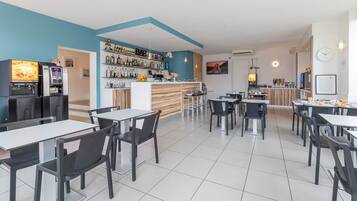 A modern cafe with a bar area, multiple seating options, and a clean, tiled floor.